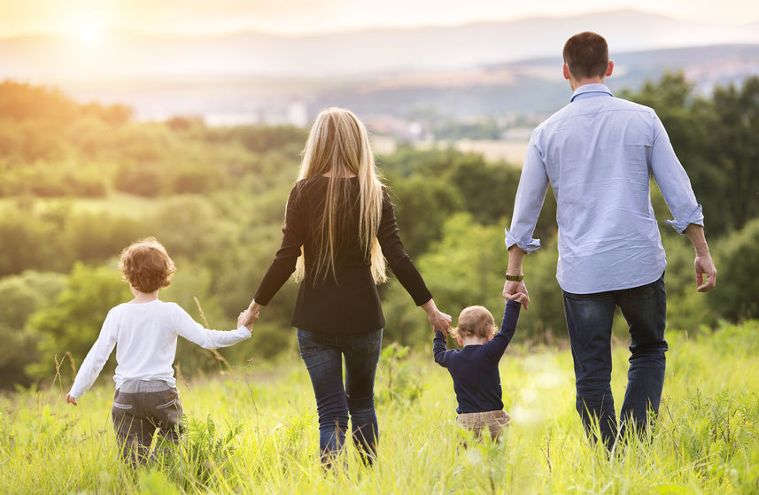 des parents et leurs deux enfants marchant dans un pré